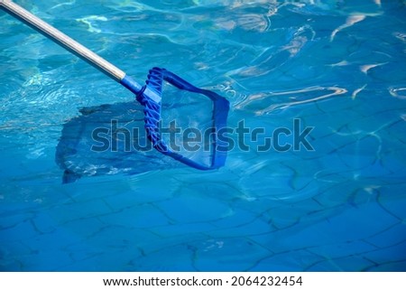 Cleaning pool from garbage with special net. Clear water with blue tint. Concept of hygiene and healthy lifestyle. Horizontal photo. Copy space. Close-up. Selective focus. Royalty-Free Stock Photo #2064232454