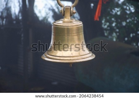Stock photo of  ancient copper or bronze bell hanging on a iron frame at Hindu temple on blur foggy background. Picture captured at sateri hill station Kolhapur ,Maharashtra, India. Royalty-Free Stock Photo #2064238454