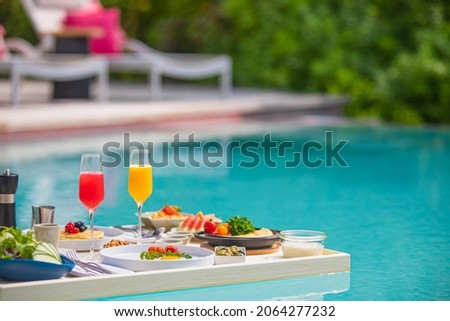 Breakfast tray in swimming pool, floating breakfast in luxury hotel. Tropical beach lifestyle. Resort swimming pool, floating breakfast in luxurious mood smoothies and fruit plate. Exotic summer diet