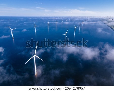 offshore windmill park with clouds and a blue sky, windmill park in the ocean aerial view with wind turbine Flevoland Netherlands Ijsselmeer. Green energy  Royalty-Free Stock Photo #2064278957