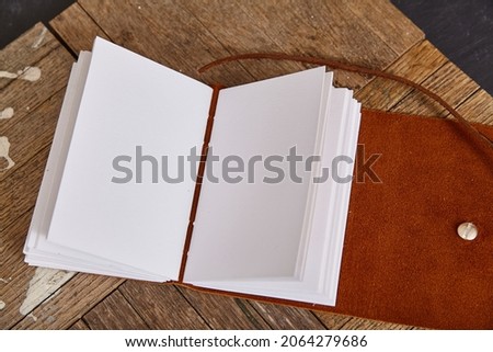 Blank pages of open journal with brown leather on wood planks