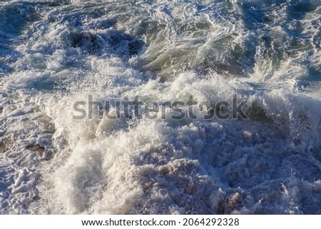 waves crashing against the rocks and foaming at sunset