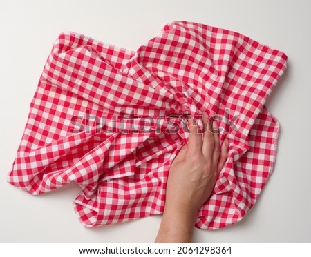 female hand holding red kitchen napkin on white table, top view