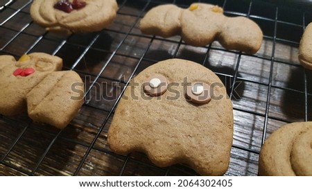 Selective focus view of the home baked Halloween Party Cutout Gingerbread Cookie in spooky ghost monster shape cooling on the baking rack. Halloween celebration