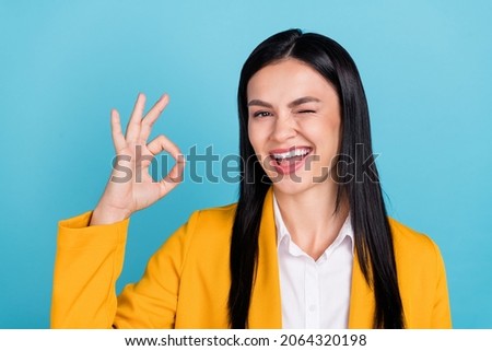 Photo of cool happy cheerful lady make okay sign deal business wink eye suggest isolated on blue color background