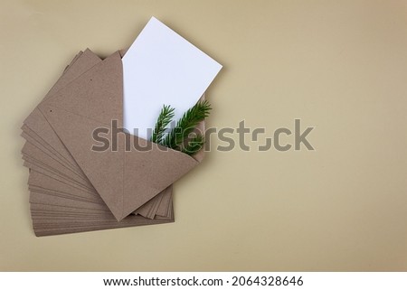 A clean white sheet in a brown envelope with a sprig of spruce. Mockup of invitation and greeting card.