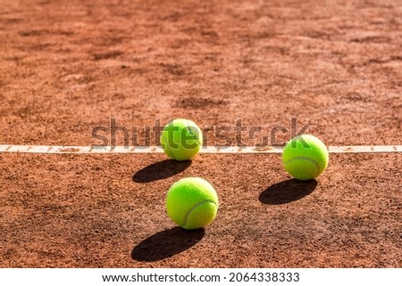 Close up of three tennis balls on a tennis clay court. Red clay court.
