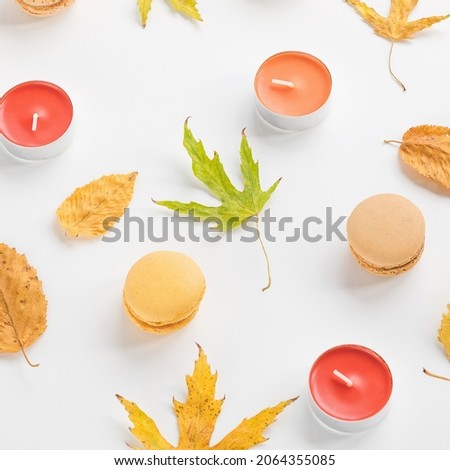 Autumn composition. Yellow leaves, candles and macaroons on white background. Autumn, fall, Halloween concept. Flat lay, top view, bright picture