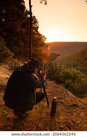 View a photographer taking photos of Hawkbill Crag (Whitaker Point) in the Ozark National Forest near the Buffalo National River at sunrise. Royalty-Free Stock Photo #2064362246