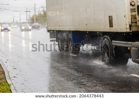 dry van trailer truck moving on a wet road with splashes during a rainy day
