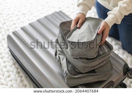 female packing things in briefcase use konmari method getting ready to travel or business trip. Smiling woman with clothes and necessary equipment suitcase storage. Stuff storage packed Royalty-Free Stock Photo #2064407684