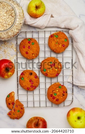 Freshly baked homemade round oatmeal cookies with chocolate and apples close-up on a marble background. Selective focus, top view and copy space