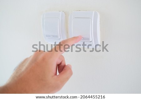 Person hand pressing home lamp switch button Royalty-Free Stock Photo #2064455216