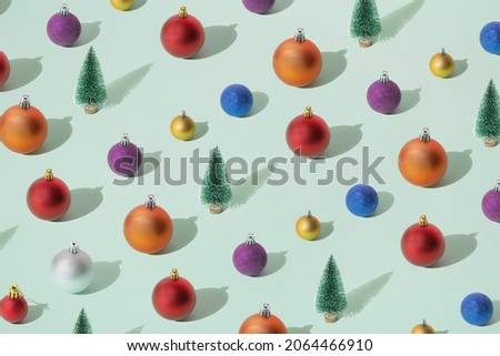 Arranged green New Year and Christmas tree with silver, yellow gold, blue, red, purple and orange bauble,  on a mint pastel background. Pattern.