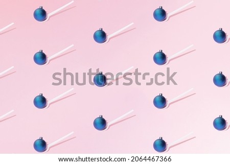 A Christmas and New Year blue bauble  stands on a white plastic fork on a pink background. Minimal design. Pattern.