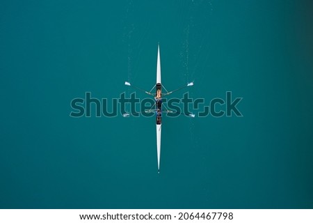 White rowing boat in motion with two women, top view. Top view of the rowing race. Aerial view of rowing. Rowing on the water aerial view. Royalty-Free Stock Photo #2064467798