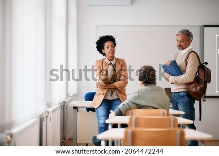 Black female teacher having consultations with adult students after a class at lecture hall.  Royalty-Free Stock Photo #2064472244