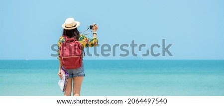 Happy traveler and tourism women travel summer on the beach.  Asia smiling people holding map and camera take photo  and relax outdoor for destination and leisure trip travel holiday.Summer Vacation Royalty-Free Stock Photo #2064497540