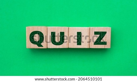 Word quiz. Wooden small cubes with letters isolated on green background with copy space available. Business Concept image.