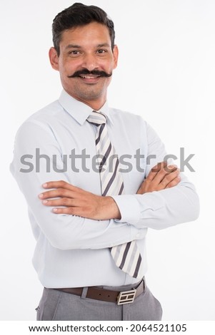 Studio shot of happy young businessman smiling with arms crossed