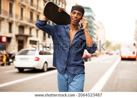  African man with skateboard. Young handsome man using the phone