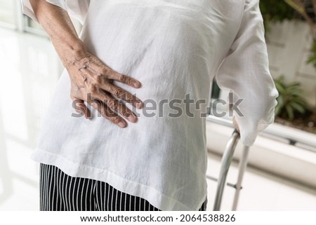 Asian senior woman with lower back pain or back muscle injury,old elderly having backache,inflammation and degeneration of muscle tissue and intervertebral discs or autoimmune diseases,health problems