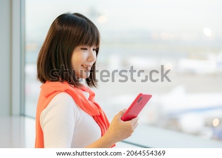 Traveller woman operating smartphone at airport