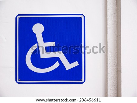 Handicapped sign with wheelchair isolated on white wall.