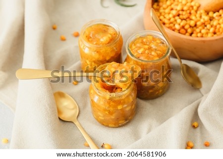 Jars of healthy sea buckthorn jam on table