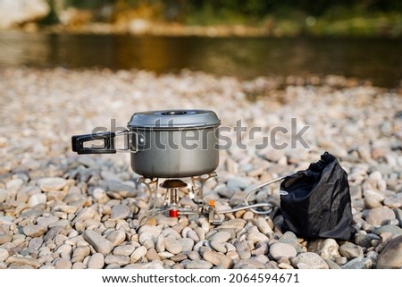 Aluminum pot for cooking on a hike. Cooking on a gas burner on the river bank. Compact lightweight equipment for hiking. High quality photo