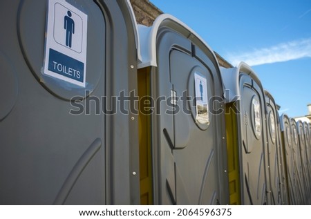 Row of dark grey portable toilets. Outdoors shot