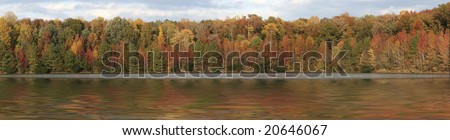a panorama picture of fall trees over water