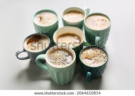 Cups of tasty coffee on light background