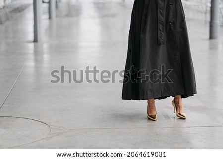 A female in a long black skirt and gold heels in a white room Royalty-Free Stock Photo #2064619031