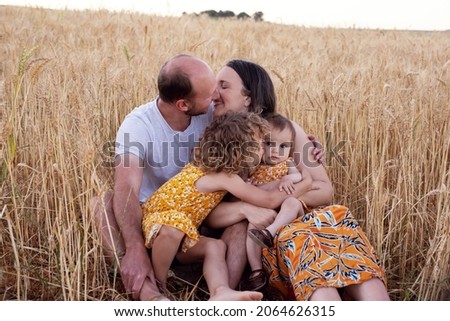 A beautiful family in a wheat field in the country. Two young girls. Loving family. Lots of laughter. 