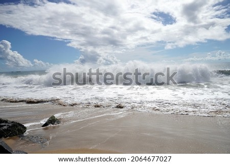 Ocean waves crashing on sandy beach.  Sea waves breaking on shore. Nature splash on summer day. Sea wave crashing on beach. Coastal storm and storm weather concept. Splashing sea water with foam.