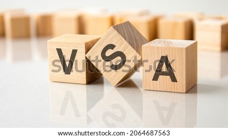 three wooden cubes with the letters VSA on the bright surface of a gray table. the inscription on the cubes is reflected from the surface of the table. business concept