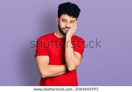 Young arab man with beard wearing casual red t shirt thinking looking tired and bored with depression problems with crossed arms. 