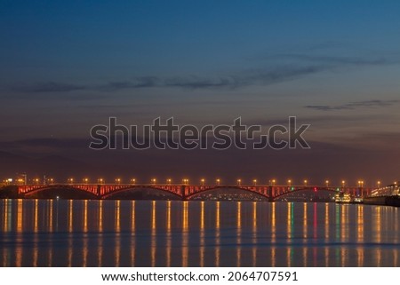 Beautiful view of a bright and colorful bridge across the river. Cityscape at night with a beautiful bridge over the river