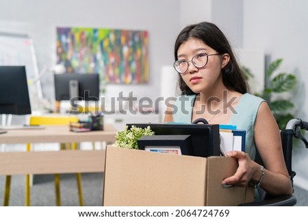 Sad disillusioned disappointed woman in glasses with regret leaves her job in the company, she was fired by disability, illness, wheelchair, injustice of employer, boss Royalty-Free Stock Photo #2064724769
