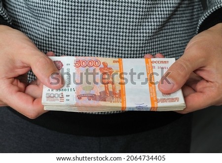 Close-up men's hands hold a wad of Russian money five thousand bills. Royalty-Free Stock Photo #2064734405