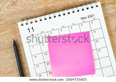 Blank sticky note on November 2021 desk calendar on wooden background for your text.