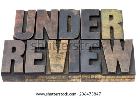 under review - isolated word in vintage letterpress wood type with ink patina
