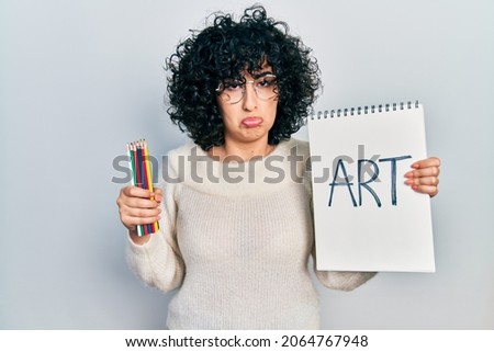Young middle east woman holding art notebook depressed and worry for distress, crying angry and afraid. sad expression. 