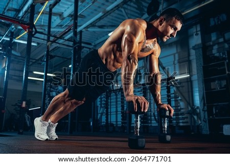 Push-ups from box. Strong athlete, bodybuilder workouts alone at sport gym, indoors. Concept of sport, activity, healthy lifestyle, strength and power. Working out with weights. Wellness, wellbeing