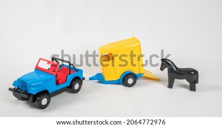 Plastic toy multicolored cars isolated on white background. A car with a van for transporting horses.