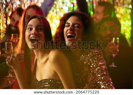 Young, happy, excited friends having fun at the party. New Year celebration gathering. Drinking alcohol, laughing, dancing. Concept of party, fun, holiday, relaxation, meeting. Copy space for ad