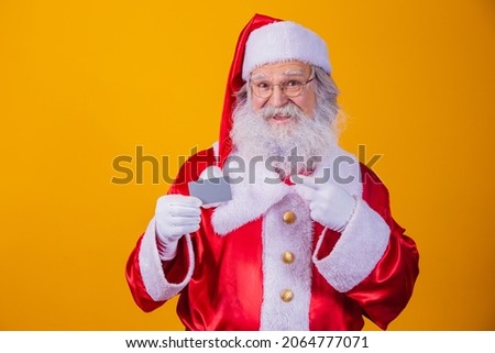 photo of Santa Claus holding a credit card on yellow background. Easy payment concept with credit or debit card. bank payment