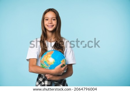 Caucasian young teenager schoolgirl pupil student holding hugging globe on geography lesson isolated in blue background. Happy Earth day! Royalty-Free Stock Photo #2064796004