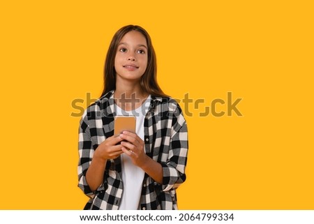 Pensive thoughtful caucasian young girl teenager student schoolkid pupil thinking dreaming about excellent marks, e-learning, social media posts isolated in yellow background.